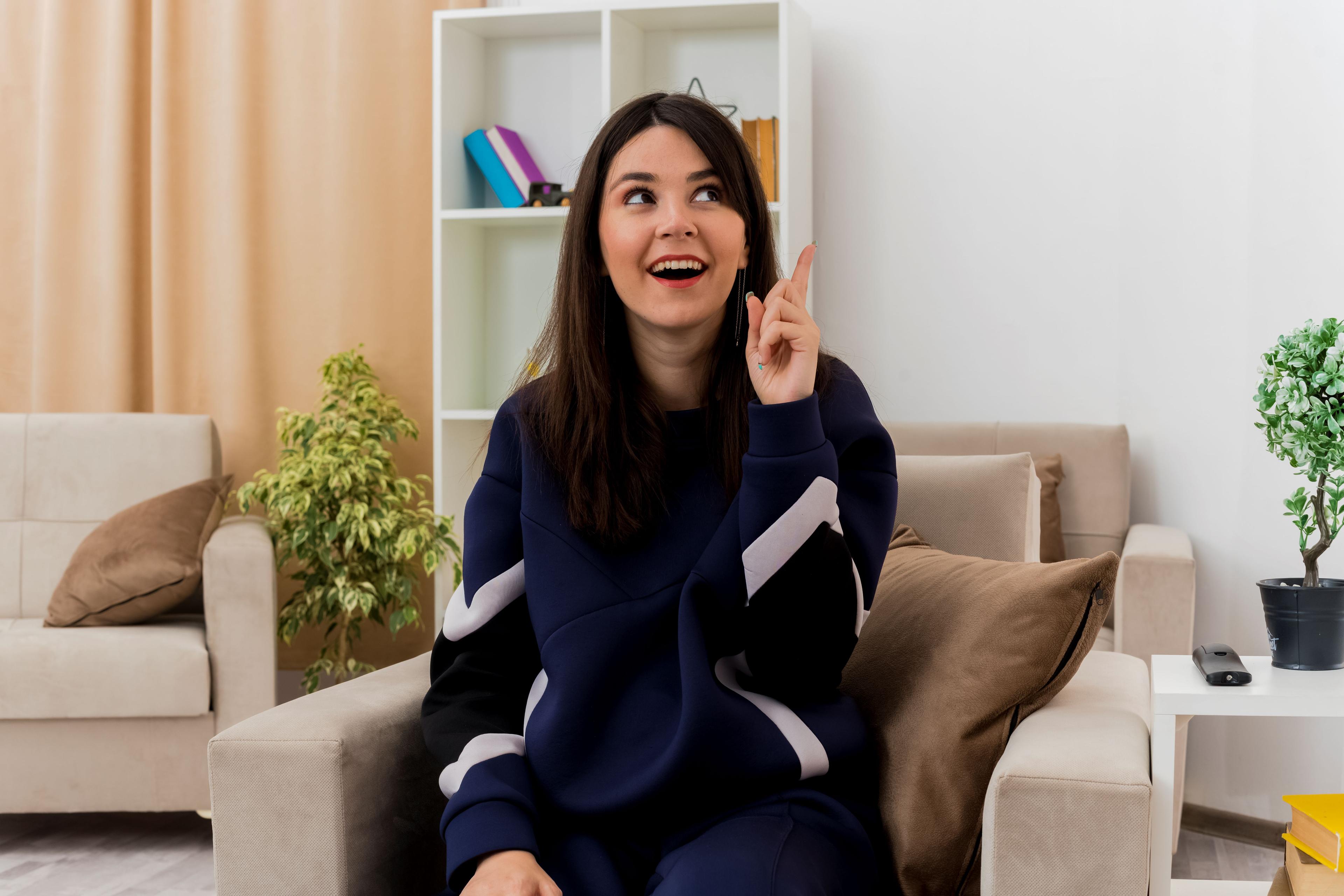 Young woman sitting happily in a modern living room, representing comfortable room for rent in Gachibowli.