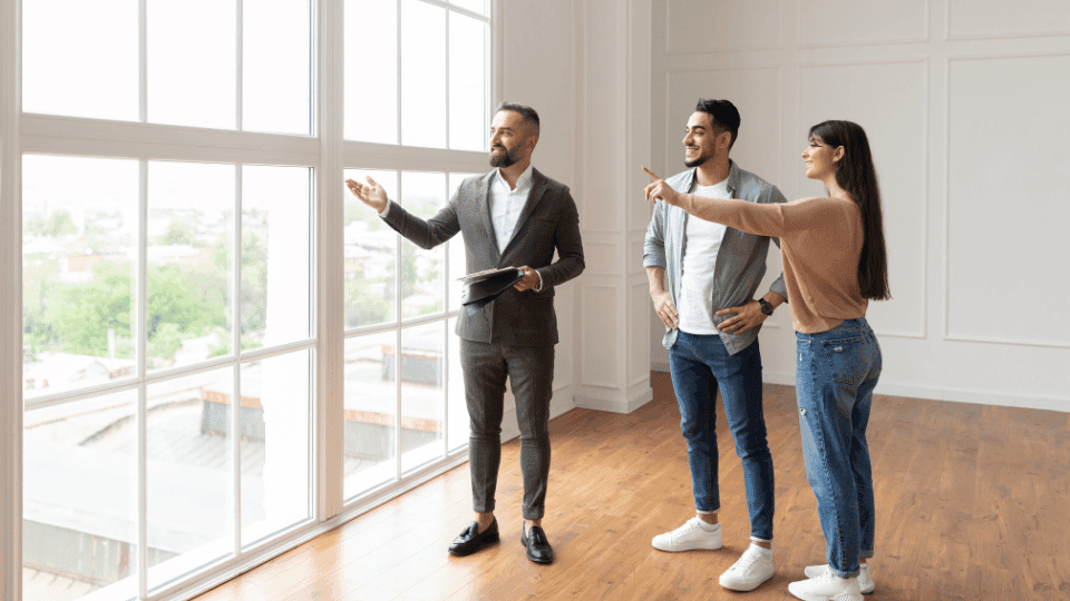 Real estate agent showing a modern, spacious room for coliving in Wakad to a young professional woman with a city view.
