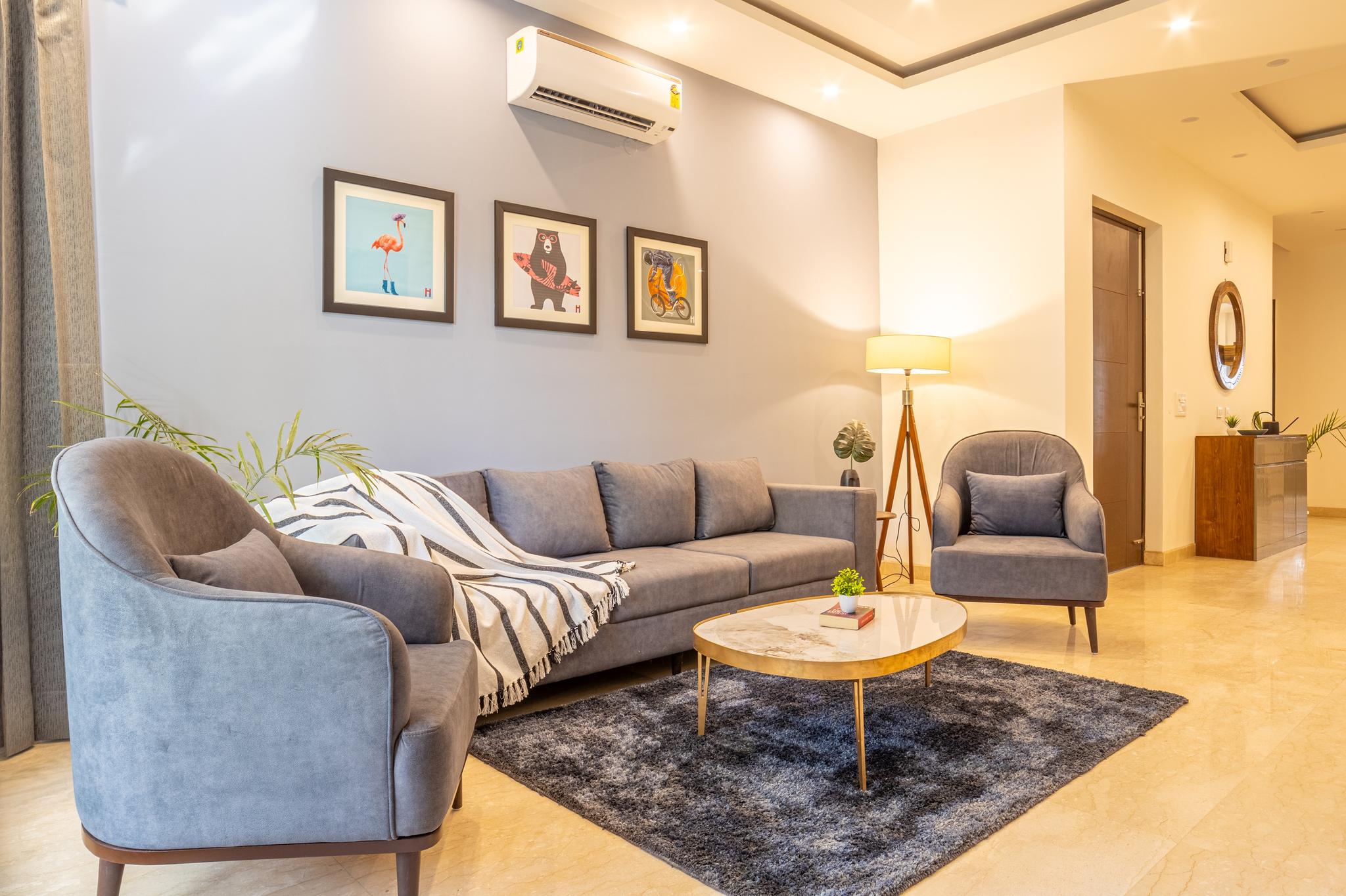 Modern living room with a grey sofa, marble coffee table, and stylish decor in a premium flat for rent in Gurgaon.