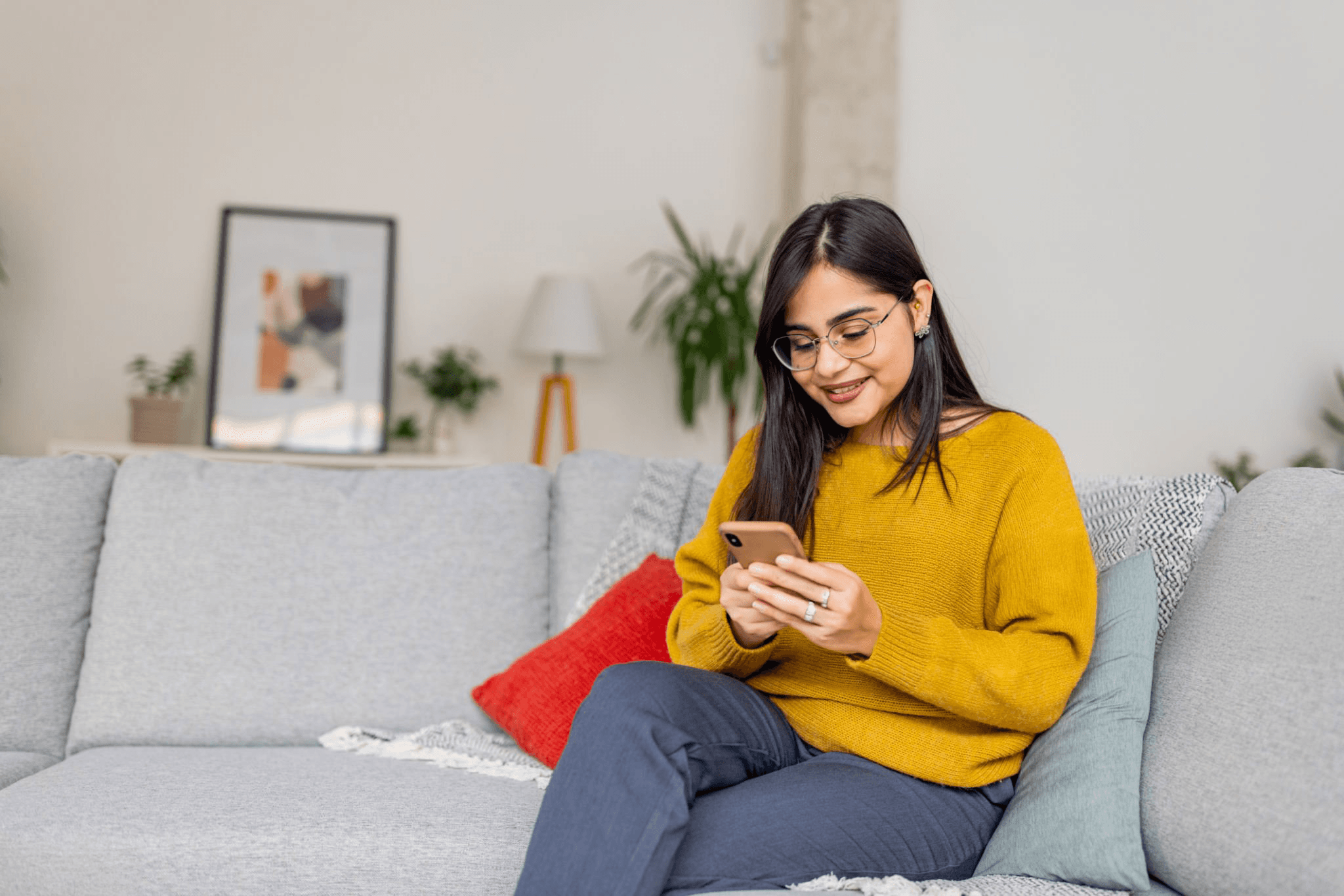 Young woman relaxing on a sofa with her phone inside modern coliving spaces in Gurgaon.